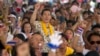 An anti-government protester raises her arm as she listens to a speech delivered by their leader Suthep Thaugsuban during a rally in Bangkok, Thailand, Saturday, May 10, 2014.