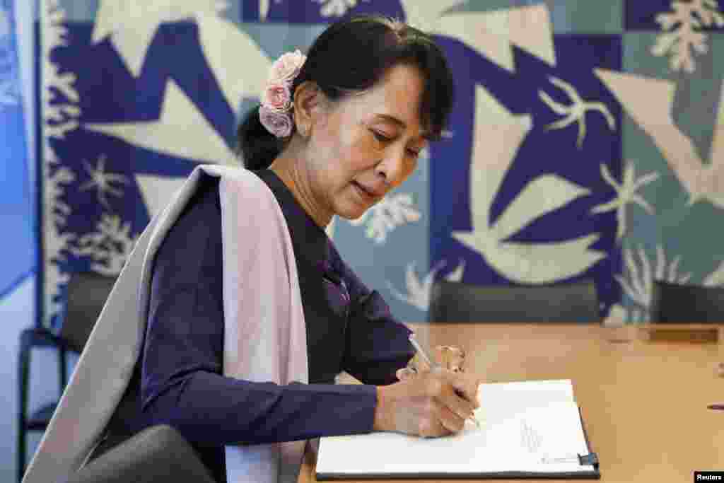Aung San Suu Kyi signs the guest book of UN Secretary-General Ban Ki-moon at the United Nations in New York, September 21, 2012. 