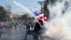 An anti-government protester throws back a tear gas canister fired by riot police in Bangkok, Thailand, Dec. 1, 2013.