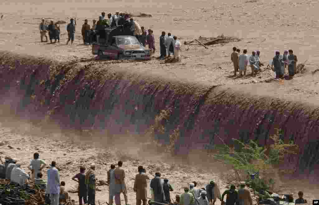 Pakistani villagers wade across a flooded road after heavy rain on the outskirts of Peshawar. Flash floods triggered by torrential rains killed dozens of people in northwest Pakistan, officials said.