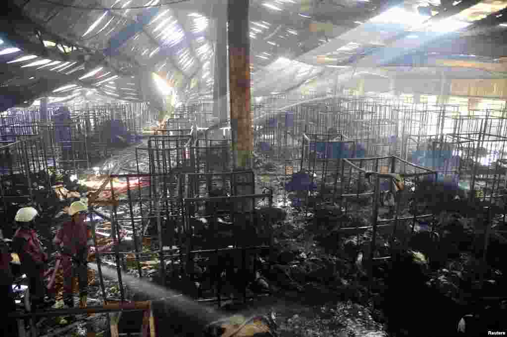 Para petugas pemadam kebakaran mencoba mengontrol api di sebuah pabrik garmen di Gazipur, Bangladesh (9/10).
