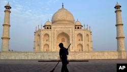 FILE - In this June 3, 2013, photo, a worker sweeps in front of Taj Mahal in Agra, India. Swarms of insects are proliferating in the heavily contaminated waters of the Yamuna River, which flows behind the 17th century monument.
