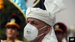 FILE - Afghan President Ashraf Ghani, wearing a mask to help curb the spread of the coronavirus, sings the national anthem at the Independence Minaret monument during the Independence Day celebrations in Kabul, Afghanistan, Aug. 18, 2020.