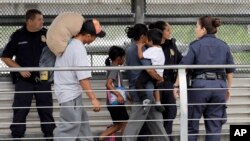 FILE - Ever Castillo (L) and his family, immigrants from Honduras, are escorted back across the border by U.S. Customs and Border Patrol agents, June 21, 2018, in Hildalgo, Texas.