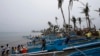 FILE - Homeless typhoon victims gather near their new fishing boats given by a religious organization along a coastal village devastated by super Typhoon Haiyan in Tacloban city, central Philippines.