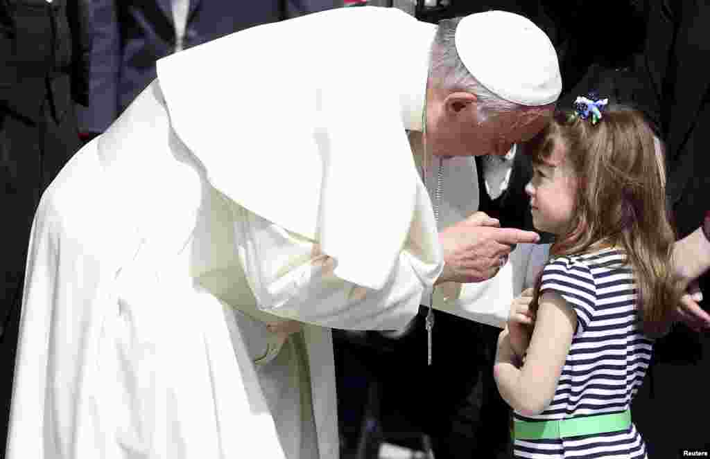 Pope Francis talks with Elizabeth 'Lizzy' Myers, a 5-year-old girl from Ohio, U.S., who suffers from a genetic disease known as Usher syndrome, which leads to blindness and hearing loss, at the end of the weekly audience in Saint Peter's Square at the Vatican.