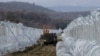 FILE - Macedonian Army vehicles move along a path between two lines of fence reinforced with razor wire, on the border line with Greece near the southern Macedonia's town of Gevgelija, Feb. 14, 2016.
