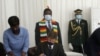 Andrew Pascoe (seated), the president of the Commercial Farmers Union of Zimbabwe, signs the agreement while President Emmerson Mnangagwa (with scarf) waits for his turn, at the State House in Zimbabwe, July 29, 2020. (Columbus Mavhunga/VOA) 