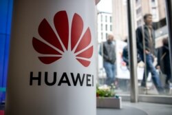 FILE - A pedestrian walks past a Huawei product stand at an EE telecommunications shop in London, April 29, 2019.
