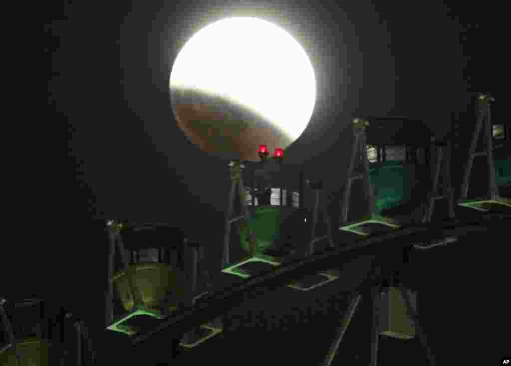 A photographer on a Ferris wheel catches the image of he Earth's shadow crossing the moon during a total lunar eclipse in Tokyo, Japan, Oct. 8, 2014.