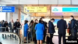 Travelers wait to be informed at the KLM Service Desk, regarding the U.S. travel ban for some European countries, in Schiphol, Netherlands, March 12, 2020. 