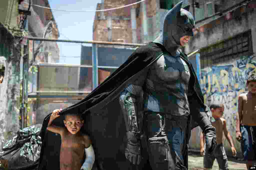 Children play around a man disguised as Batman at the Favela do Metro slum, area just near the Maracana stadium, in Rio de Janeiro, Brazil. Families living in this shantytown within a stone's throw of Rio 's mythical Maracana stadium refuse to have their homes demolished as part of a project to renovate the district before the FIFA World Cup circus pitches camp in June.