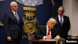 FILE - President Donald Trump signs the initial executive order for a U.S. travel ban, Jan. 27, 2017, at the Pentagon.
