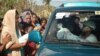 A volunteer in a passing car hands out water to typhoon victims, Cebu, Philippines, Nov. 15, 2013. (Steve Herman/VOA)