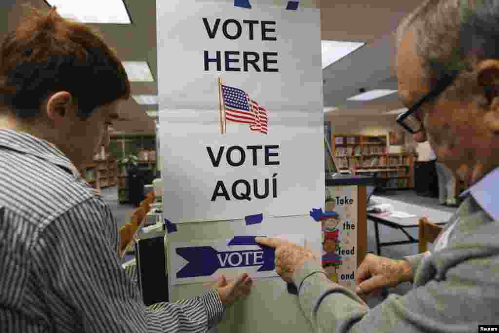 Petugas pemilu memasang tanda tempat pemilihan suara di perpustakaan Sekolah Dasar Spring Hill di McLean, negara bagian Virginia. (Reuters/Kevin Lamarque)