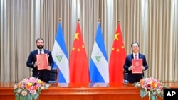 In this photo released by China’s Xinhua News Agency, Laureano Ortega Murillo, son of and advisor to Nicaraguan President Daniel Ortega, left, and Chinese Vice Foreign Minister Ma Zhaoxu display their jointly signed communique on the resumption of diploma