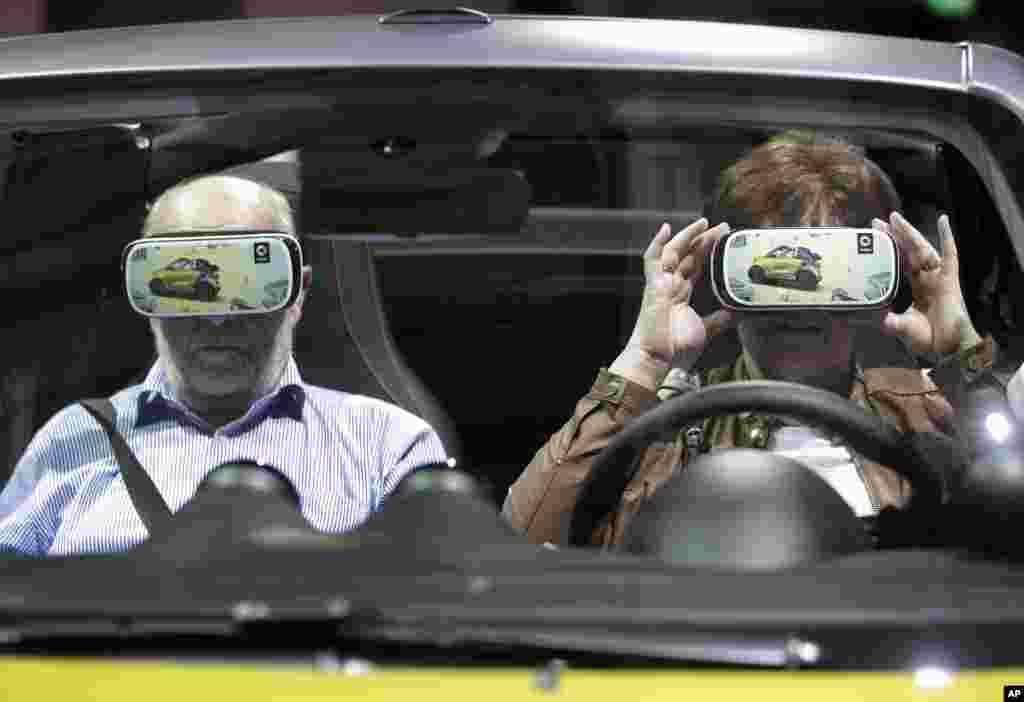 A woman touches a virtual reality 3D glasses as she and a man sit in a car prior to the shareholders' meeting of the Daimler AG in Berlin, Germany.