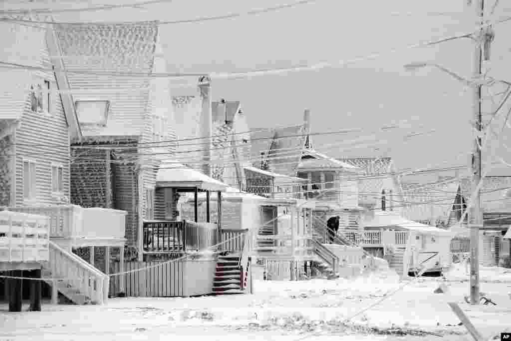 Dexter Newcomb begins cleanup at his house in Scituate, Mass., Jan. 28, 2015, the day after a winter storm left his neighborhood coated in frozen sea spray and sand. 