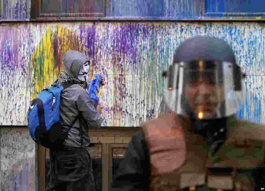 A protestor uses a water gun to spray with colored paint on the Public Revenue Office building during an anti-government protest in downtown Skopje, Macedonia.