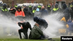 Polisi menyemprotkan meriam air untuk menghalau aksi protes di tengah restriksi untuk menanggulangi pandemi Covid-19 di Amsterdam, Belanda, 24 Januari 2021.