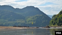 A yellow flag along the Mekong River marks the spot chosen for construction of the Luang Prabang dam near Houaygno village, Laos, Nov. 4, 2019. (Zsombor Peter/VOA)