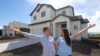 In this April 27, 2019, photo, millennials Andy and Stacie Proctor stand in front of their new home in Vineyard, Utah. 