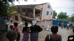 Warga di lokasi sekolah yang rusak akibat gempa berkekuatan 5,9 SR di Gros Morne, Haiti, 7 Oktober 2018. 