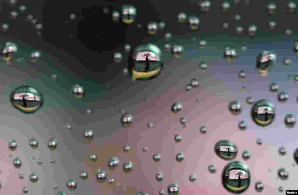 Raindrops on a car window reflect a man walking past a stock index board in Tokyo, Japan.