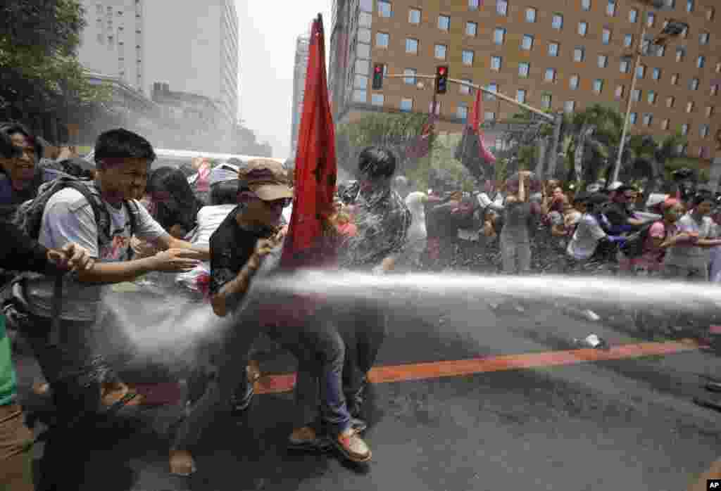 Police train their fire hose at protesters as the latter try to force their way closer to U.S. Embassy for a rally against next week&#39;s visit of U.S. President Barack Obama in Manila, Philippines.