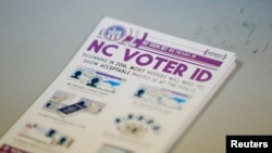 FILE - A pile of government pamphlets explaining North Carolina's controversial "Voter ID" law sits on table at a polling station.