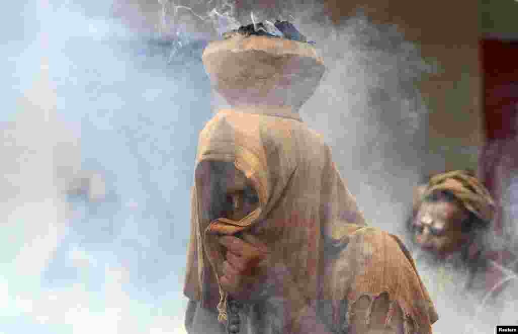 A Sadhu or a Hindu holy man covers his face as an earthen pot with burning &quot;Upale&quot; (or dried cow dung cakes) on his head during a prayer ceremony at the Simhastha Kumbh Mela in Ujjain, India.