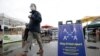FILE - A man walks past a sign advising social distancing, at the Ferry Plaza Farmers Market, in San Francisco, California, March 28, 2020.
