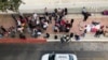 FILE - Migrants gather to hear names called from a waiting list to claim asylum in the U.S., at the U.S.-Mexico border in Tijuana, Mexico, Nov. 10, 2019.