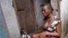 A woman sits with a baby, in the West Point area that has been hardest hit by the Ebola virus spreading in Monrovia, Liberia, Monday, Aug. 25, 2014. A Liberian doctor who was among three Africans to receive an experimental Ebola drug has died, the country