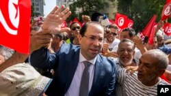 FILE - Tunisian Prime Minister Youssef Chahed, center, arrives to submit his candidacy for the upcoming early presidential elections in Tunis, Tunisia, Aug. 9, 2019.