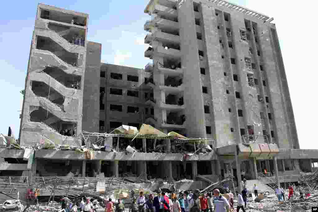 Syrian gather in front of the facade of the damaged military intelligence building where two bombs exploded.