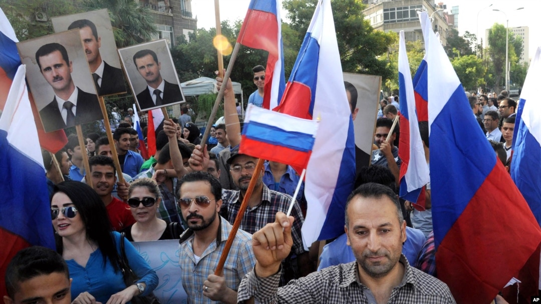 This photo from the Syrian official news agency SANA shows Syrians rallying in front of the Russian Embassy in Damascus to show their thanks to Russia for its intervention in Syria, Oct. 13, 2015. But few Syrians who leave their country are finding Russia welcoming. 