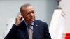FILE - Turkish President Tayyip Erdogan adjusts earphones at a news conference.