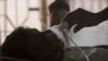 FILE -A relative adjusts the oxygen mask of a tuberculosis patient at a TB hospital on World Tuberculosis Day in Hyderabad, India, March 24, 2018. 