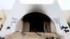 A man walks at the headquarters of Islamist militant group Ansar al-Sharia after it was set on fire by protesters after clashes between members of the group and a Libyan army special forces unit in the Ras Obeida area in Benghazi, Nov. 25, 2013.