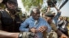 FILE - Uganda's main opposition leader Kizza Besigye, center, is arrested by police and thrown into the back of a blacked-out police van which whisked him away and was later seen at a rural police station, outside his home in Kasangati, Uganda, Feb. 22, 2016. 
