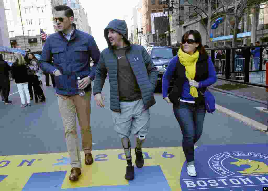 Boston Marathon bombing survivor Jeff Bauman, center, walks over the marathon finish line on the third anniversary of the bombings in Boston.